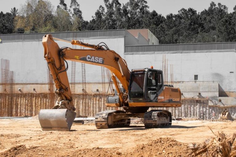 Bagger auf einer Baustelle vor einer betonierten Kellerwand